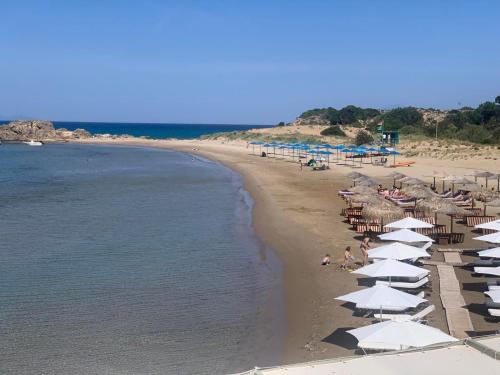 a beach with umbrellas and people sitting on the beach at Alkionisnest in Arkoudi