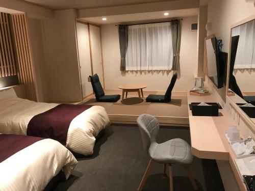 pokój hotelowy z 2 łóżkami, stołem i krzesłami w obiekcie Aizu Tsuruya Hotel w mieście Aizu-Wakamatsu