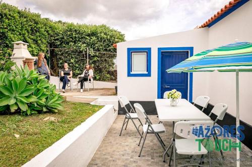 um pátio com uma mesa, cadeiras e um guarda-sol em Casa da Rocha em Angra do Heroísmo