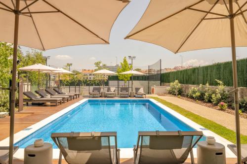 a swimming pool with chairs and umbrellas next to a pool at BFRESH Hotel - Padel, Pool & Fitness - Adults Only in Porto