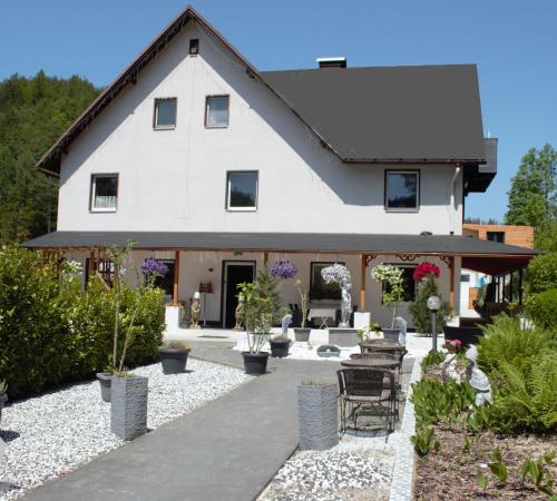 una grande casa bianca con cortile con piante di Waldpension Pfeiferhaus a Warmensteinach