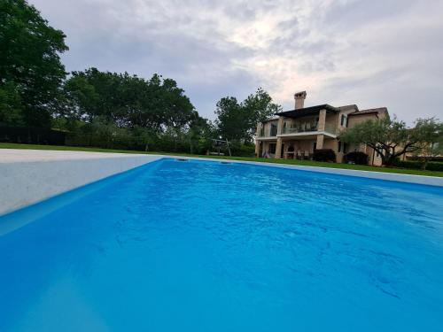 duży niebieski basen przed domem w obiekcie Apartments Villa Sotlar with pool w mieście Umag