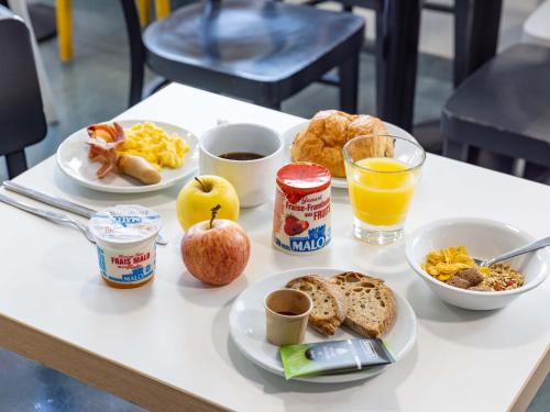 - une table avec des aliments et des boissons pour le petit-déjeuner dans l'établissement B&B HOTEL Rennes Sud Chantepie, à Rennes