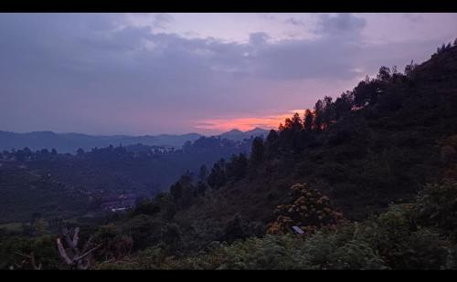 a view of a mountain with a sunset in the background at Joy House - 1 bhk Cozy entire house in Ooty