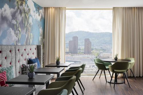 un restaurante con mesas y sillas y una gran ventana en Renaissance Zurich Tower Hotel, en Zúrich