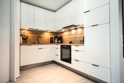 a white kitchen with wooden walls and white cabinets at Fewo 3-13 Ostsee in Kappeln