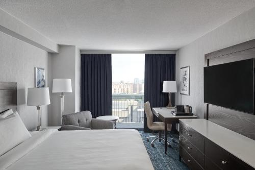 a hotel room with a bed and a desk and a television at Chelsea Hotel Toronto in Toronto