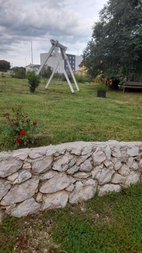 une sculpture dans un champ à côté d'un mur de pierre dans l'établissement Apartments Kruno, à Međugorje