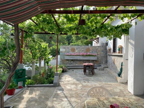 eine Terrasse mit einem Tisch und Stühlen unter einer Pergola in der Unterkunft Η θεα traditional house in Makrinítsa