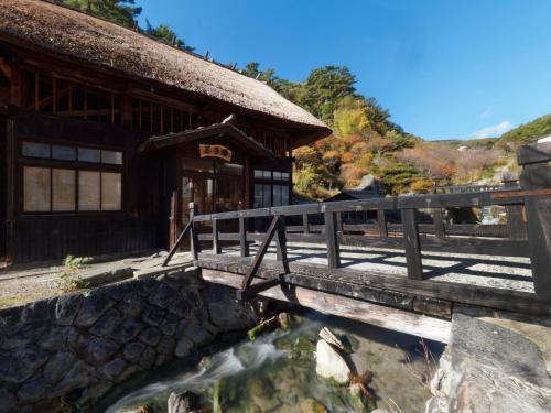 un ponte su un laghetto di fronte a un edificio di Ryokan Tamagoyu a Machi-niwasaka