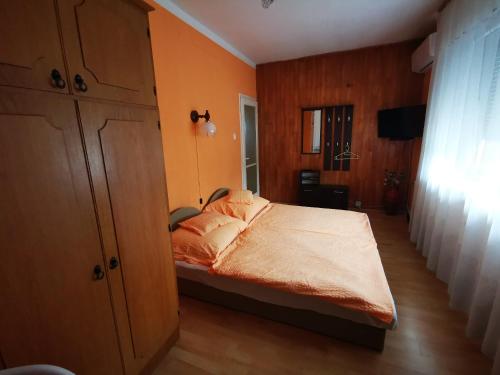 een slaapkamer met een bed met oranje muren bij Paksy Apartman in Harkány