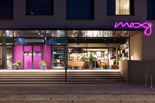 uma fachada da Macy Store à noite com um sinal de néon roxo em Moxy Rust em Rust