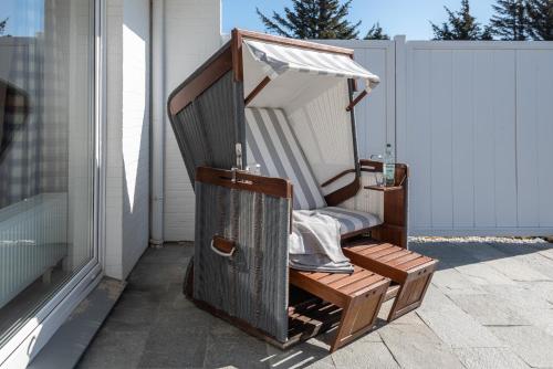 une chaise en bois assise sur le côté d'une terrasse couverte dans l'établissement Nordseegruß 1, à Wenningstedt