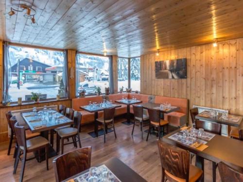 um restaurante com paredes e mesas e cadeiras de madeira em Résidence Hôtel Rent - Megève Centre em Megève