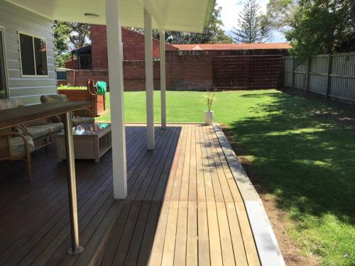 une terrasse couverte d'une maison avec une pelouse dans l'établissement Magnolia Cottage, à Coffs Harbour