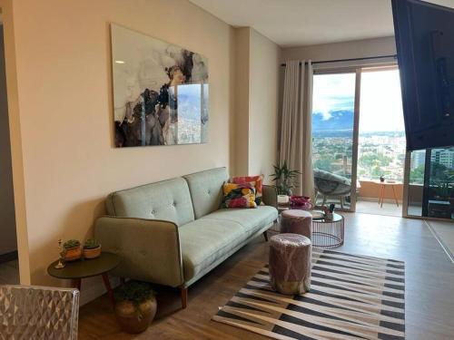 ein Wohnzimmer mit einem Sofa und einem großen Fenster in der Unterkunft Depto a estrenar increíble vista 180º Cocha in Cochabamba