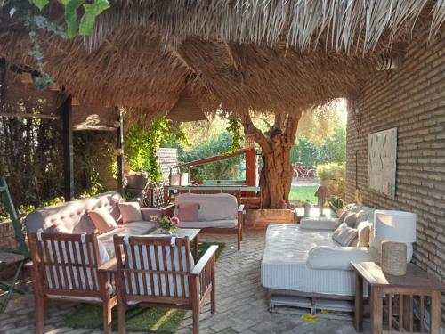 a patio with couches and chairs under a straw roof at Dormir entre limones, Casa de invitados en vivienda familiar in Dos Hermanas