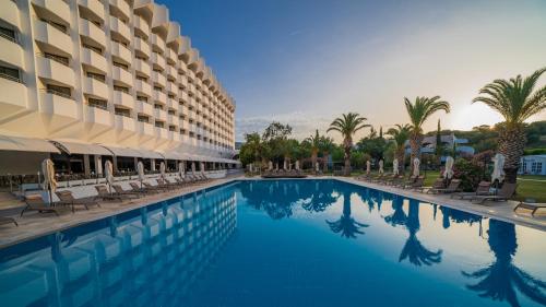 a swimming pool in front of a hotel with palm trees at Club Beyy Resort Hotel - Ultra All Inclusive in Izmir