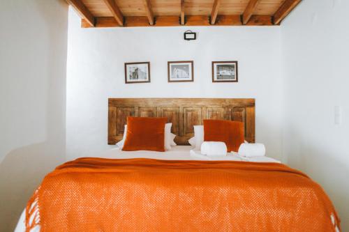 ein Schlafzimmer mit einem großen Bett mit einer orangefarbenen Decke in der Unterkunft Casa do Castelo in Lourinhã