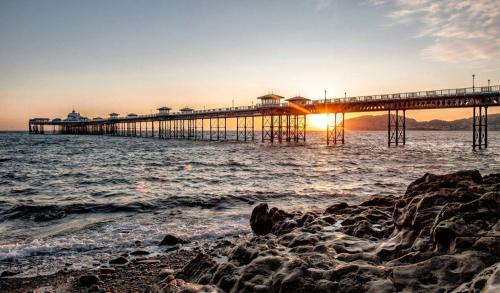 molo z zachodem słońca nad wodą w obiekcie Elsinore Hotel Llandudno w mieście Llandudno