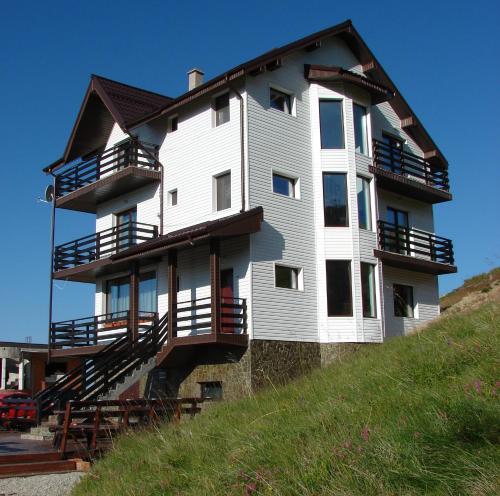 een groot wit gebouw bovenop een heuvel bij Cabana Transalpina in Ranca