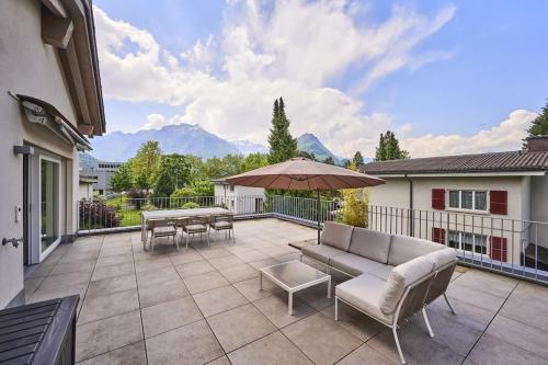 patio z kanapą, stołami i parasolem w obiekcie Terrace Vista Interlaken w mieście Interlaken