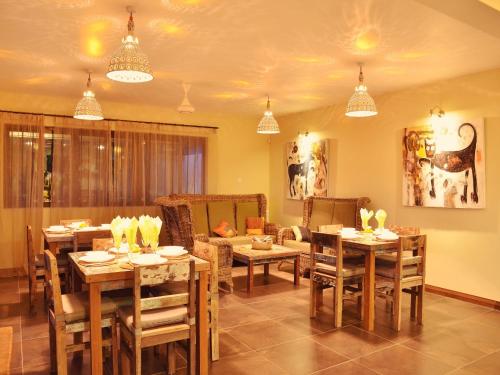 a dining room with tables and a couch at Happy Days Guest House in Le Morne