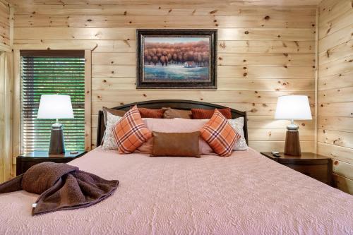 een bed in een kamer met houten wanden en 2 lampen bij Mountain Retreat Game Room, BBQ, & Scenic Views in Sevierville