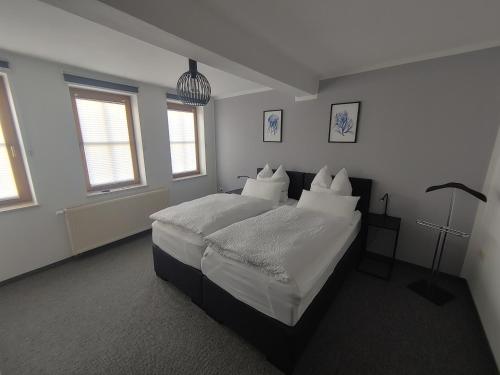 a bedroom with a bed with white sheets and pillows at Haus Blumenampel in Schmalkalden