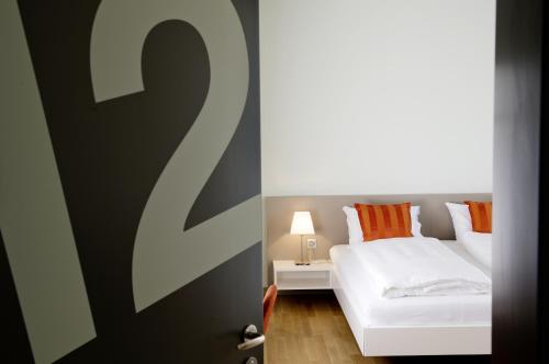 ein Schlafzimmer mit einem weißen Bett und orangefarbenen Kissen in der Unterkunft Gästehaus Hunziker in Zürich