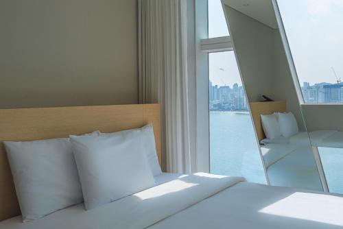 un letto con cuscini bianchi in una stanza con finestra di Hotel Marine view a Busan