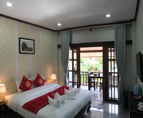 um quarto com uma cama grande e uma varanda em Villa KhounSok Sunset em Luang Prabang