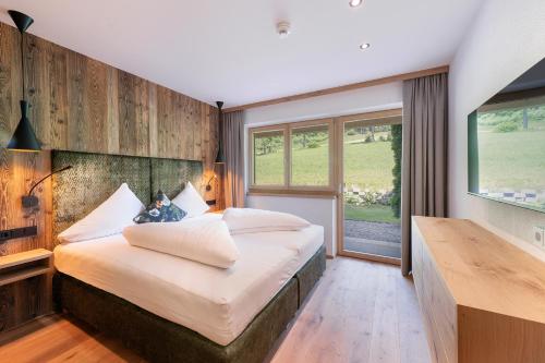 ein Schlafzimmer mit einem großen Bett und einem großen Fenster in der Unterkunft Hotel AlpenSchlössl in Söll