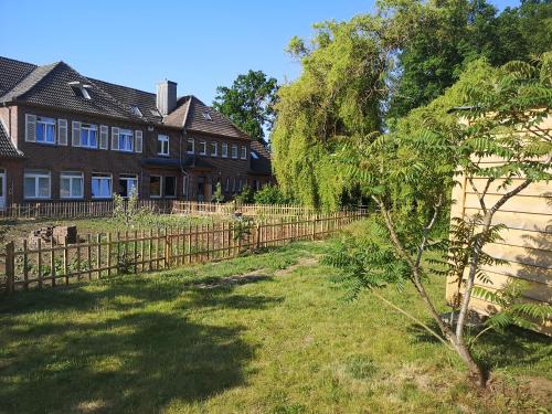 ein Haus mit einem Zaun vor einem Hof in der Unterkunft Gästehaus Maria Rast in Suderburg