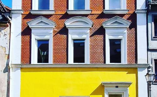 um edifício amarelo com cinco janelas num edifício de tijolos em Alte Färberei - Wohnen in der Altstadt em Kulmbach