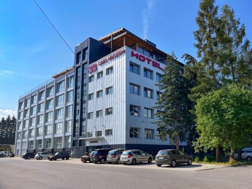 un edificio de hotel con coches aparcados en un aparcamiento en HOTEL DOUBLE RED CARS Museum, en Brezno