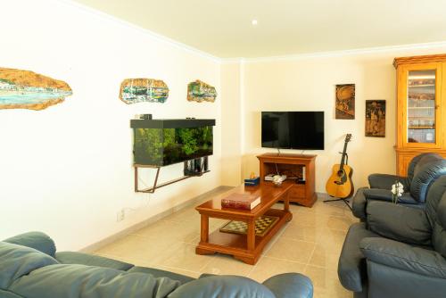 ein Wohnzimmer mit einem blauen Sofa und einem TV in der Unterkunft Family Comfort House in Seixal