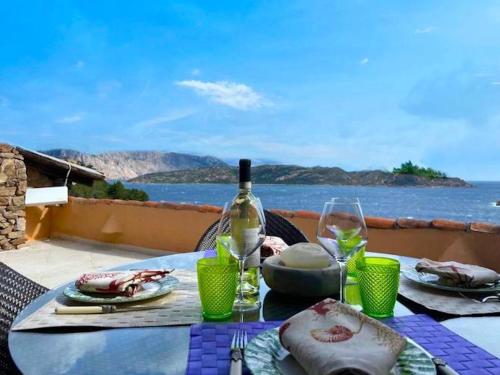 - une table avec une bouteille de vin et des assiettes de nourriture dans l'établissement San Teodoro Punta Est Magnifico Trilocale Vista Mare, à Cap Coda Cavallo