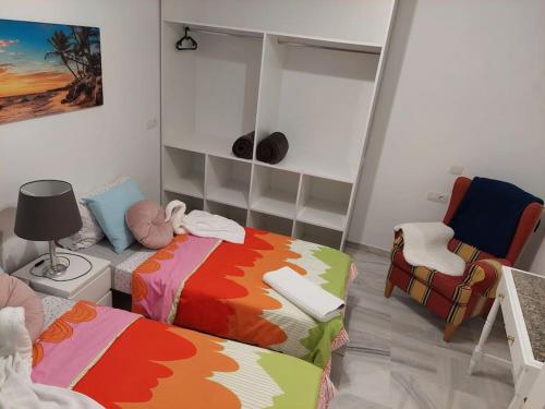 um pequeno quarto com 2 camas e uma cadeira em Central apartment in Arrecife - 1 or 2 bedrooms em Arrecife