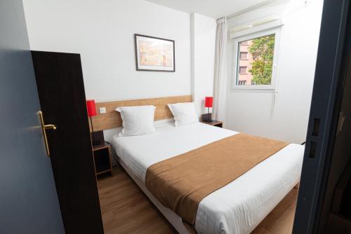 um quarto com uma cama com lençóis brancos e uma janela em Apparthotel Privilodges Lyon Lumière em Lyon