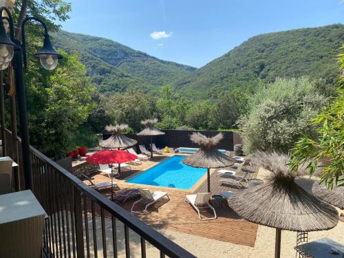 un balcón con una piscina con sombrillas y sillas en Le Belvedere, en Vallon-Pont-dʼArc