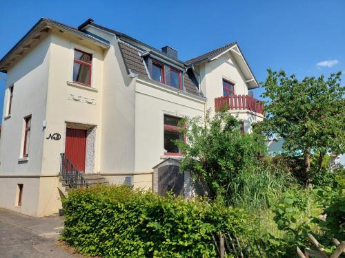 a white house with red windows and a tree at Monteurzimmer bei der Gärtnerei in Grünendeich