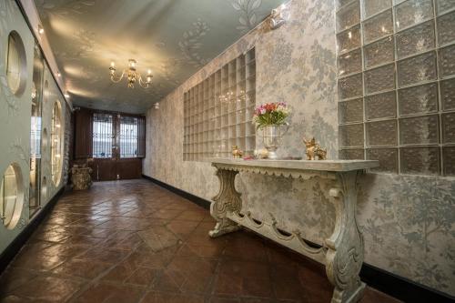 un pasillo con una mesa con flores en la pared en Casa Cavassa Centro Histórico Cusco, en Cusco