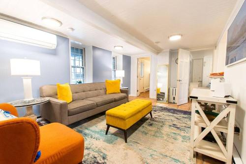 a living room with a couch and a yellow stool at Condo with Wading Pool Dog Welcome in Provincetown