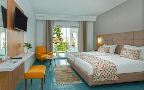 um quarto com uma cama, uma secretária e uma televisão em Djerba Holiday Beach em Midoun