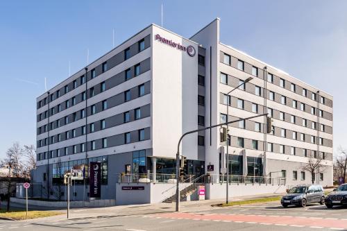 duży biały budynek z samochodami zaparkowanymi przed nim w obiekcie Premier Inn Nürnberg City Nordost w Norymberdze