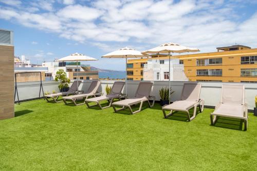 d'une terrasse sur le toit avec des chaises et des parasols. dans l'établissement Sholeo Lodges La Cícer Flats, à Las Palmas de Gran Canaria