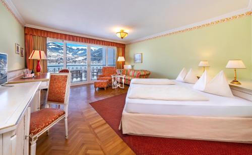 um quarto de hotel com uma cama grande e uma secretária em Grand Hotel Zell am See em Zell am See