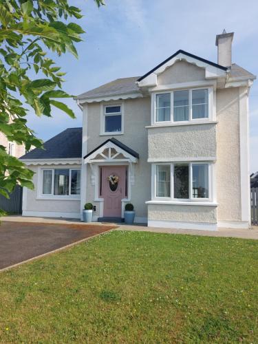 een groot wit huis met een voortuin bij Grá na Farraige in Enniscrone