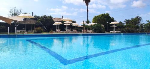 ein großer blauer Pool mit Sonnenschirmen und Tischen in der Unterkunft Hotel Relax in Syrakus